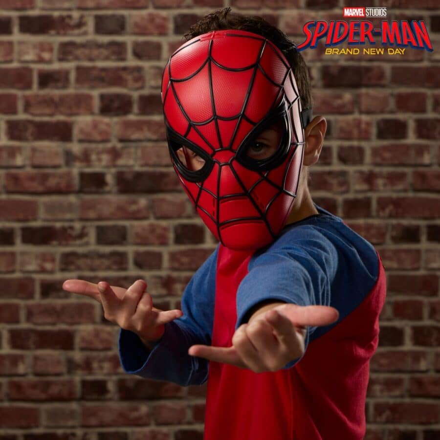 Child in a red and blue shirt wearing a Spider Man mask pointing at the camera against a brick wall Marvel Spider Man branding in the top right