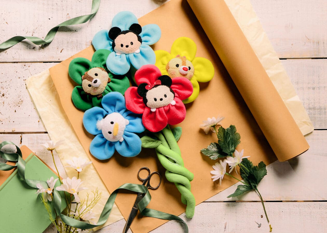 Colorful plush flower clips with Mickey Mouse style faces arranged on gift wrap with ribbons and flowers outside the bouquet