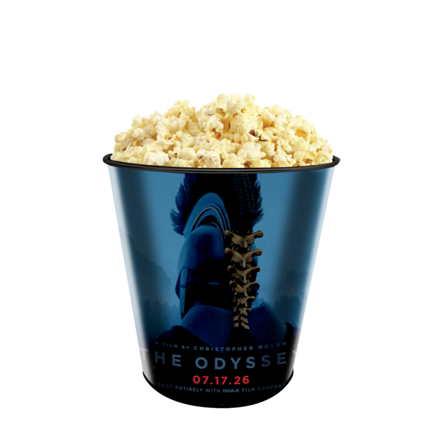 Buttered popcorn piled high in a blue film themed bucket against a black background overflowing at the top