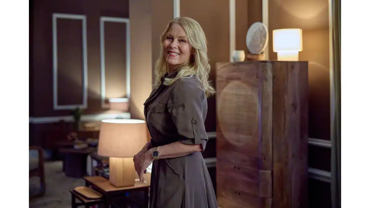 Say Oui To Romance in Paris Is Always a Good Idea on Hallmark+ Review7 Fantasy Land News Smiling woman with blonde hair wearing a gray coat in a warmly lit living room