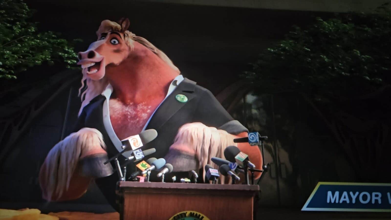 Anthropomorphic horse in a suit speaks at a press conference behind a wooden podium with many microphones