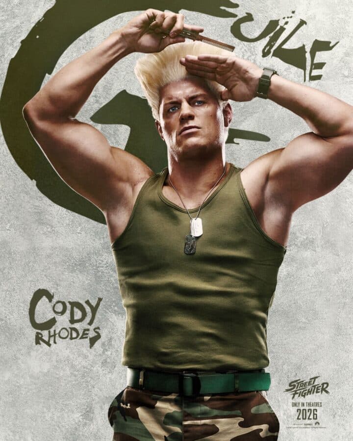 Muscular man in a green tank top and camo pants posing with hair styling tool dog tags and a green belt visible against a graffiti style background