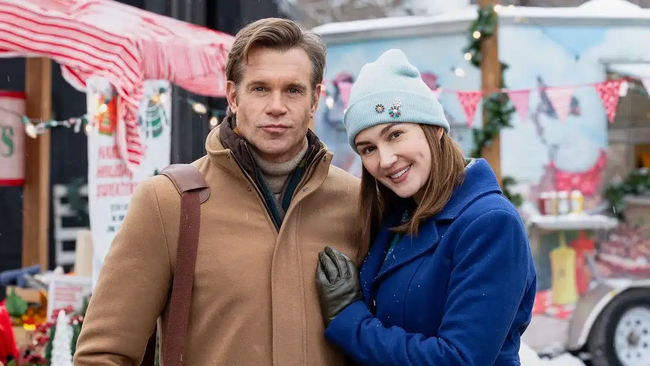 Couple posing together at a festive winter market smiling at the camera