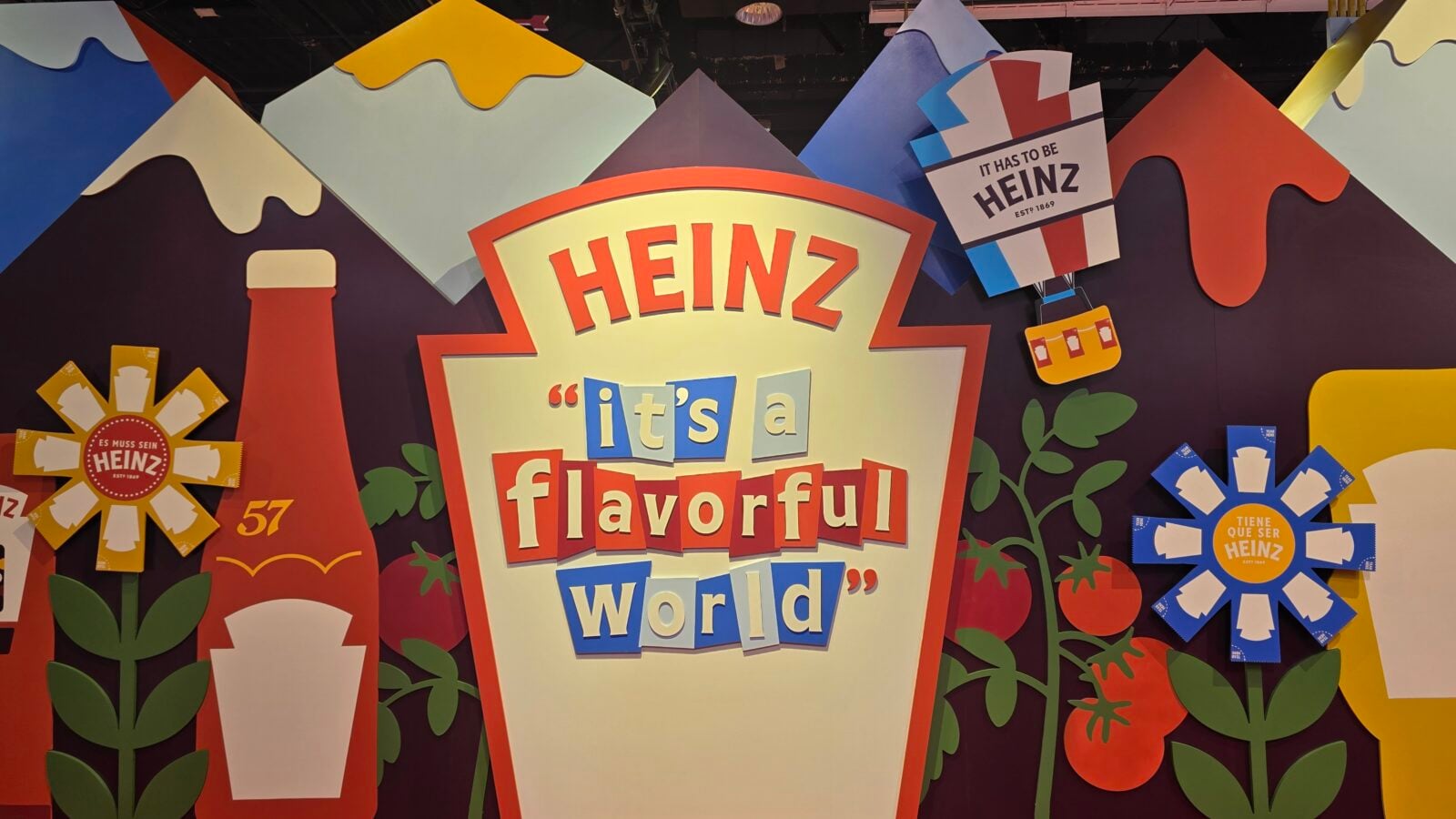 Vibrant Heinz mural with the slogan its a flavorful world surrounded by colorful shapes and flowers