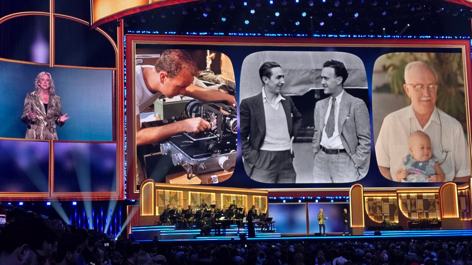 Stage with a female host on the left oversized collage panels show a vintage camera operator two men in suits and a man holding a baby during a televised event
