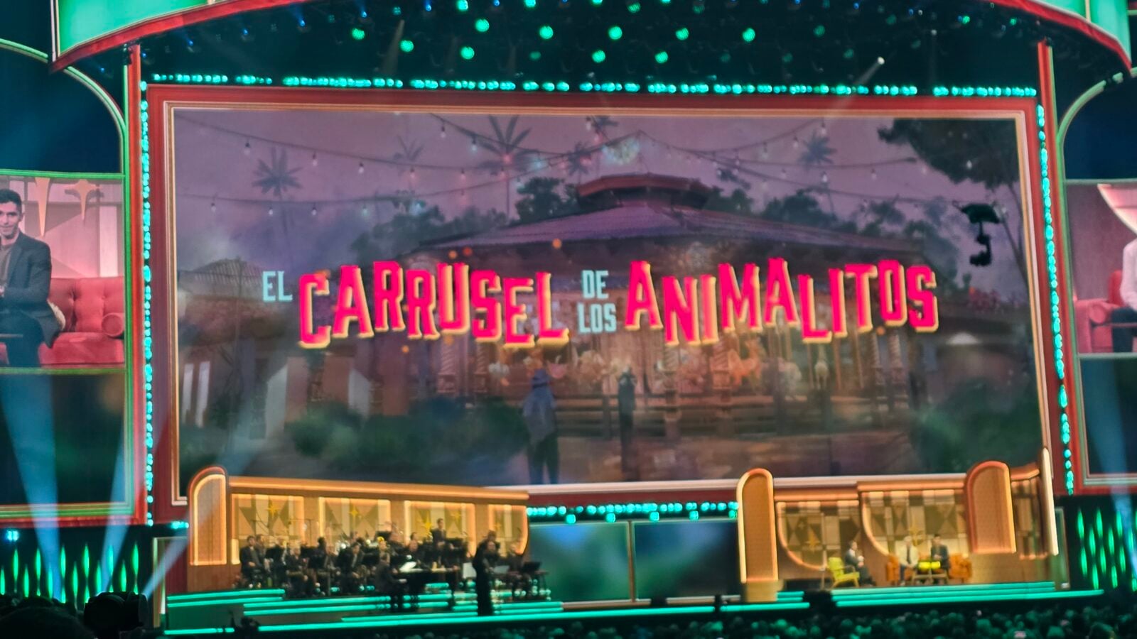 Colorful TV studio stage with a large screen reading El Carrusel de los Animales and musicians seated below