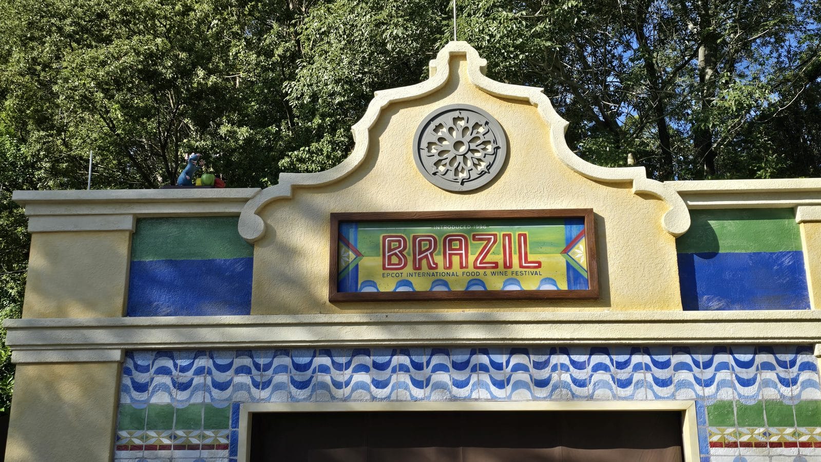 Decorative entrance arch with a circular vent and a bright BRAZIL festival sign flanked by colorful wall murals