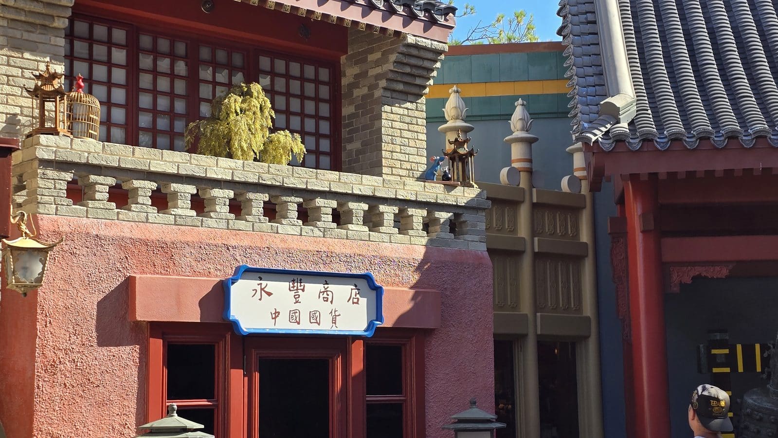 Traditional Chinese storefront with red doors stone balustrade decorative lanterns and a blue framed sign with Chinese characters outside on a sunny day