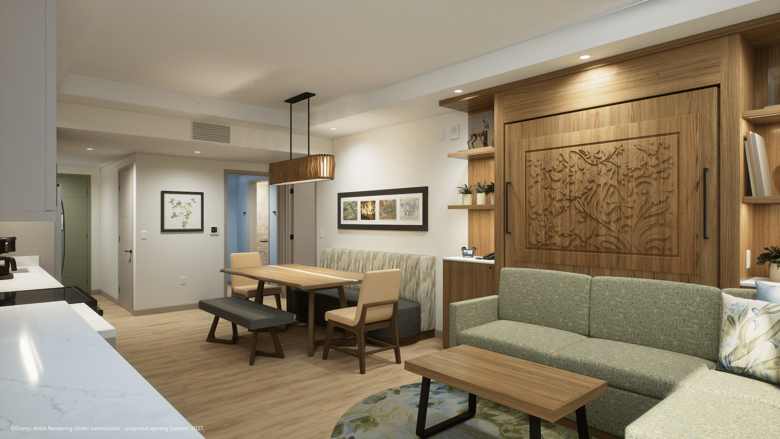 Modern open plan living and dining area with a large wooden carved cabinet green sofa and a rectangular wood dining table under a pendant light