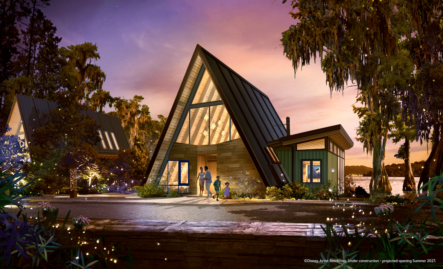 A frame house with triangular glass wall at sunset family entering the home by a wooden path with trees and a lake nearby under construction