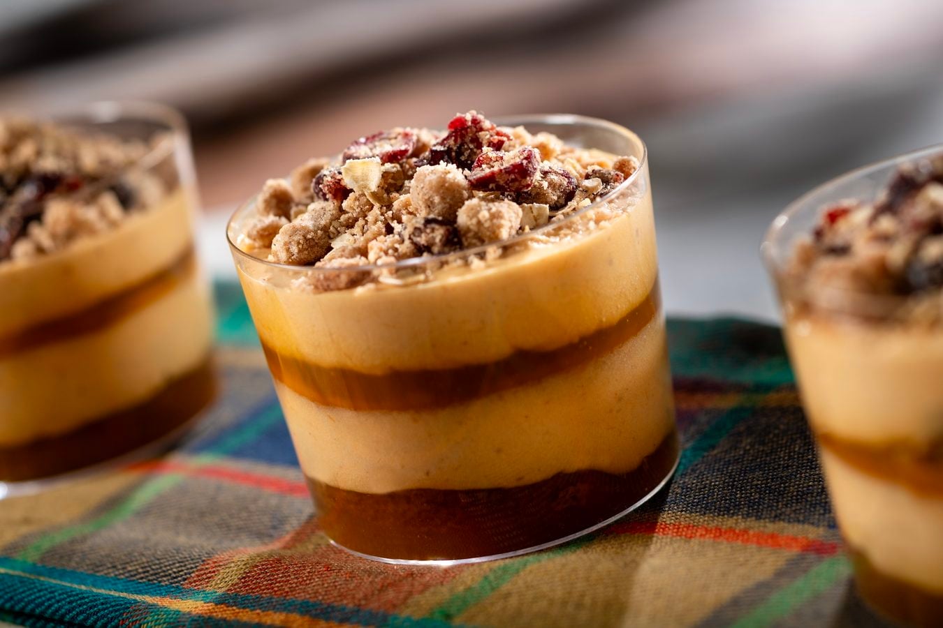 Layered dessert in a glass with crumb topping and a dark base on a colorful cloth