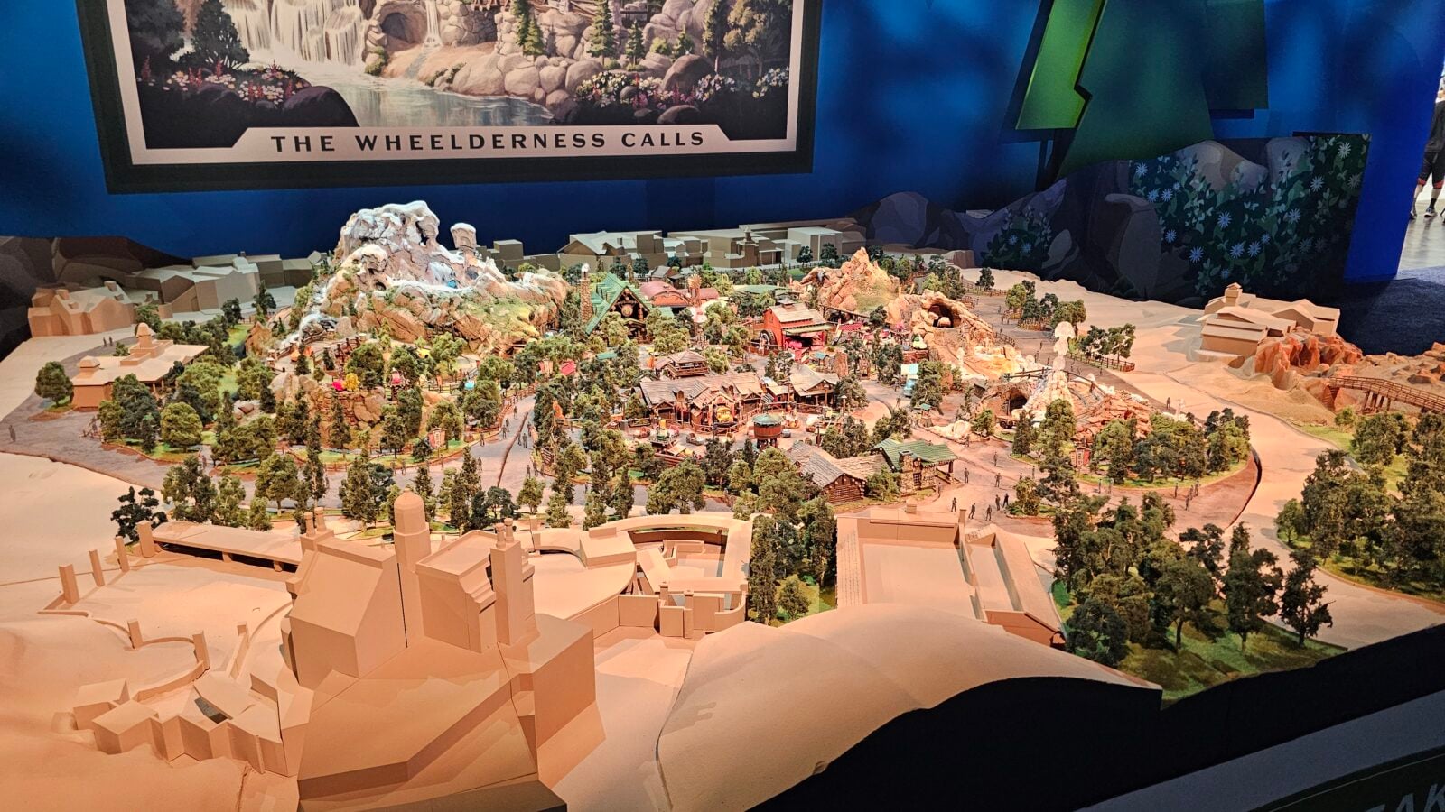 A detailed miniature mountain village diorama with trees rocky cliffs and winding roads and buildings across a desert like landscape
