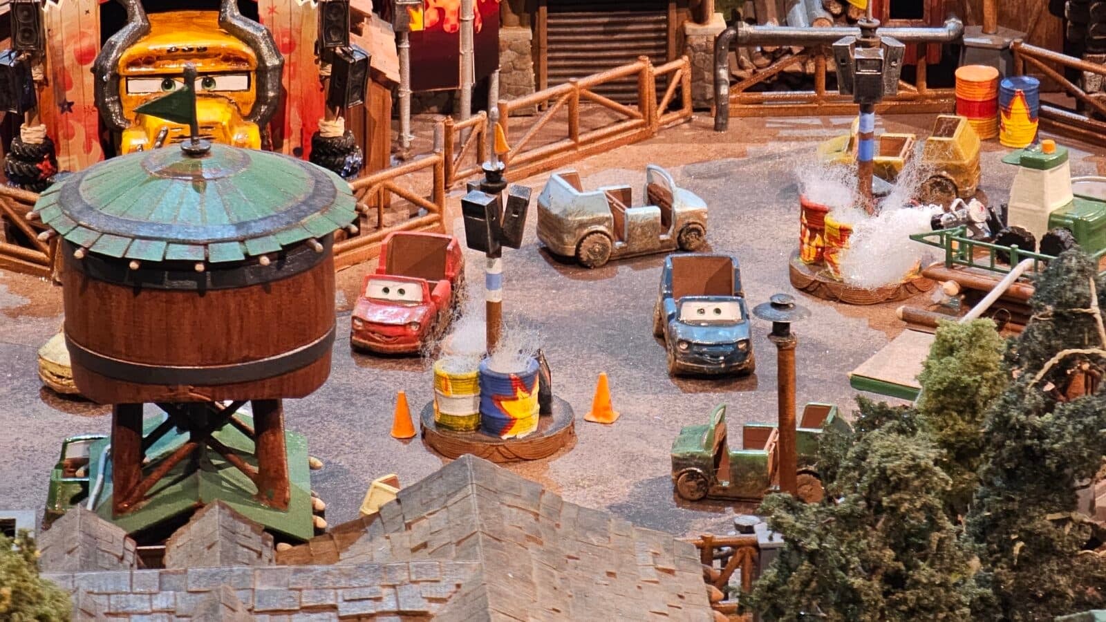 Colorful miniature amusement park scene with toy cars on a water splash track and a green roofed water tower in the foreground