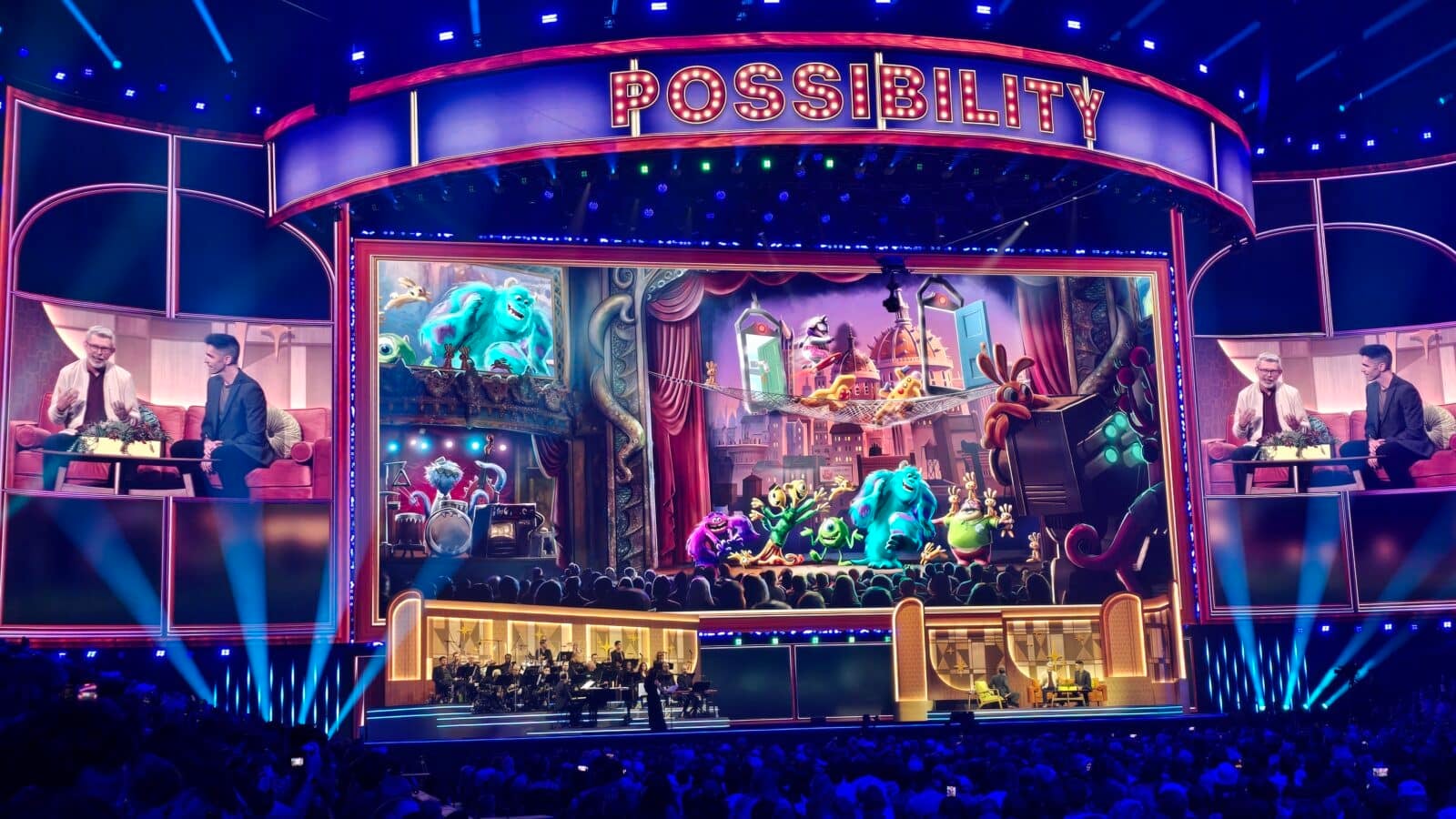 Colorful theater stage with a large illuminated POSSIBILITY sign cartoon monsters performing and an audience in front of an orchestra pit beneath the stage