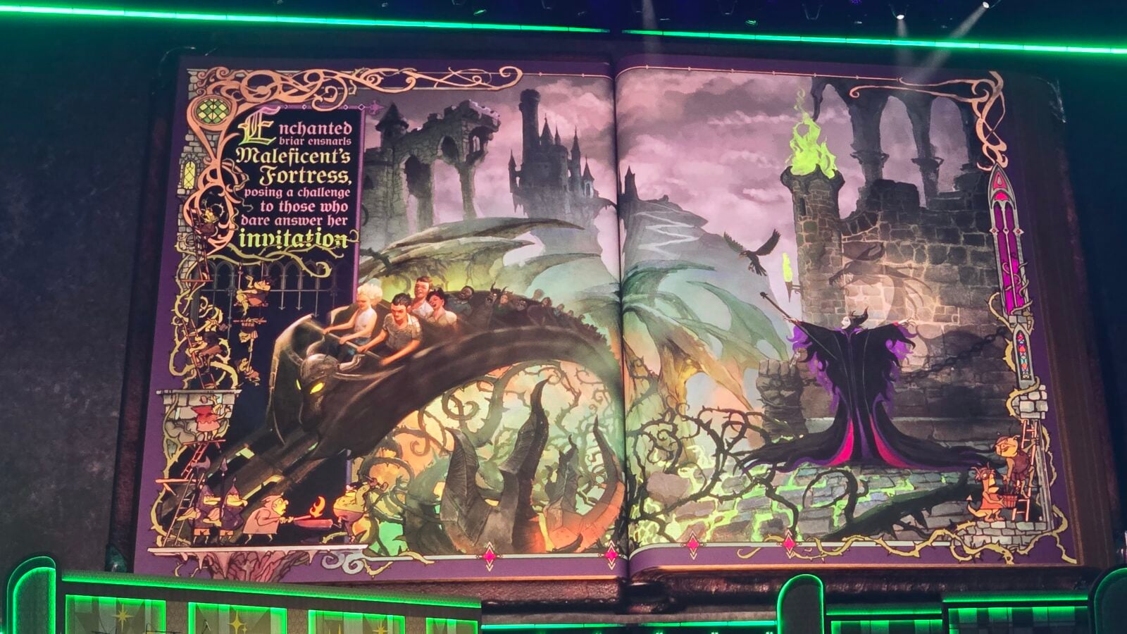 Open fantasy book illustration featuring a purple border left page with ornate text about Maleficents Fortress and a group riding a dragon in front of a ruined castle