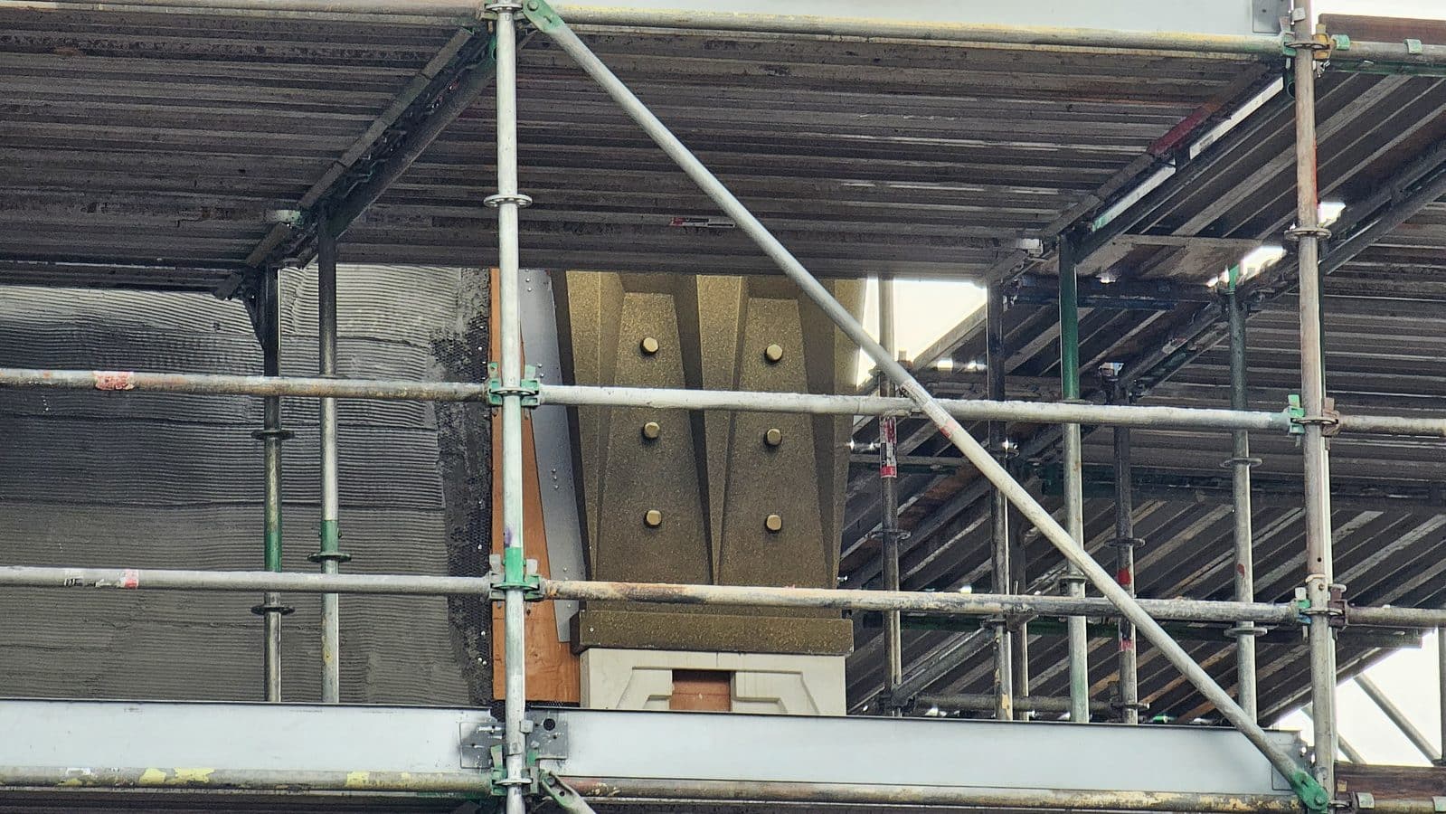 Construction scaffolding with metal poles and braces surrounding a building under renovation