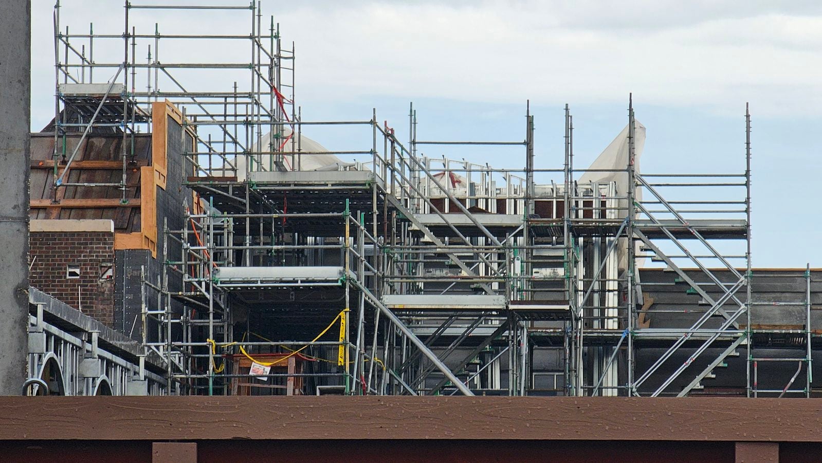 Construction site with extensive metal scaffolding around a brick building under renovation