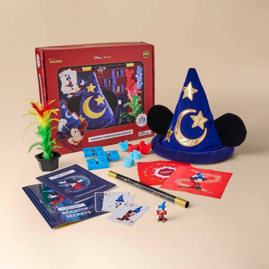 Magic show kit on a beige background a red Disney Magic box blue starry wizard hat coloring books a wand cards and colorful feathers