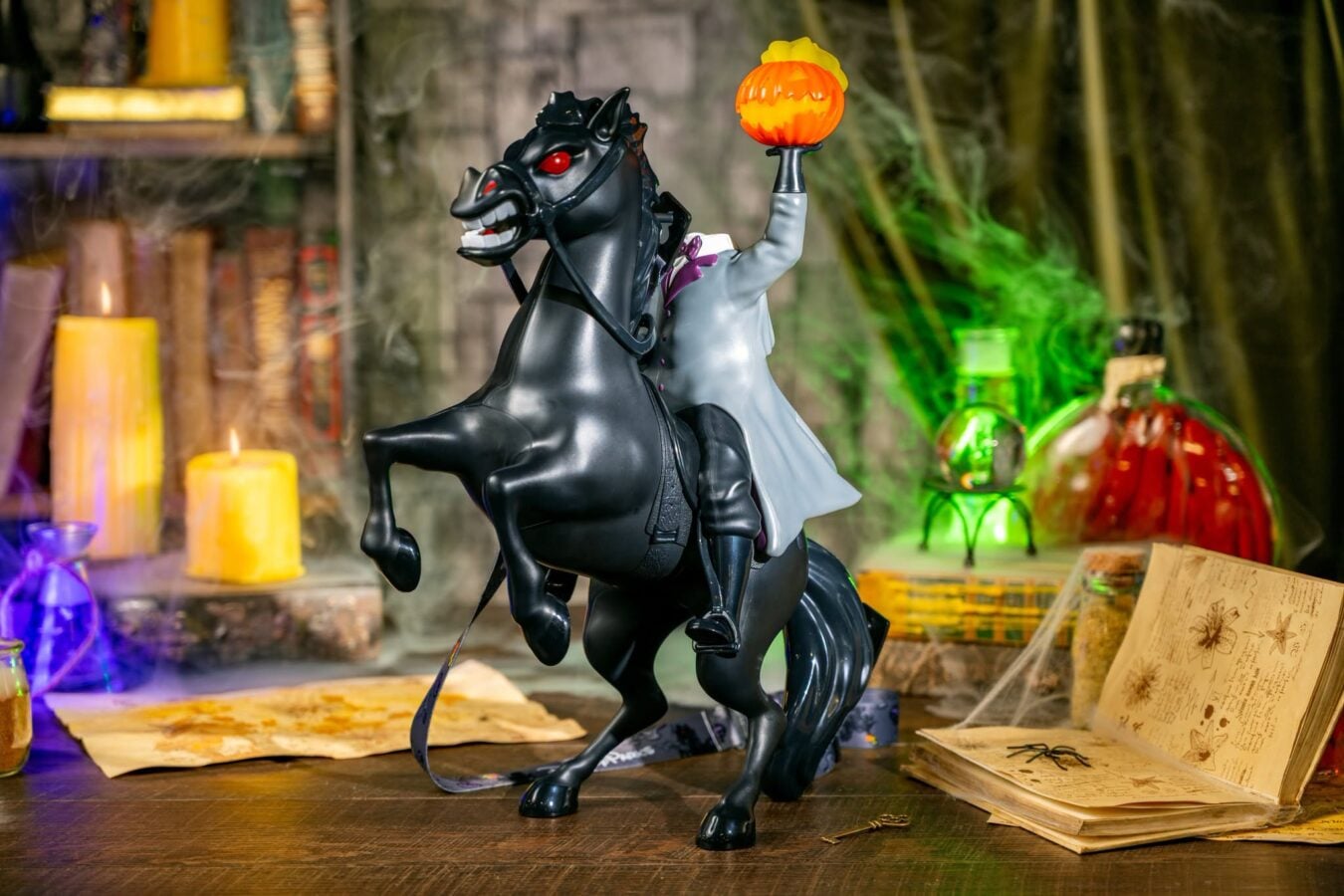 Mechanical black horse statue with rider raising an orange pumpkin lantern in a Halloween display colorful props and stage backdrop