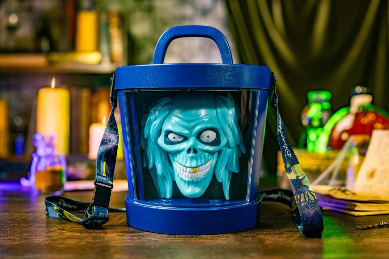Blue skull mask inside a blue protective helmet with straps on a wooden table background blurred with colorful objects