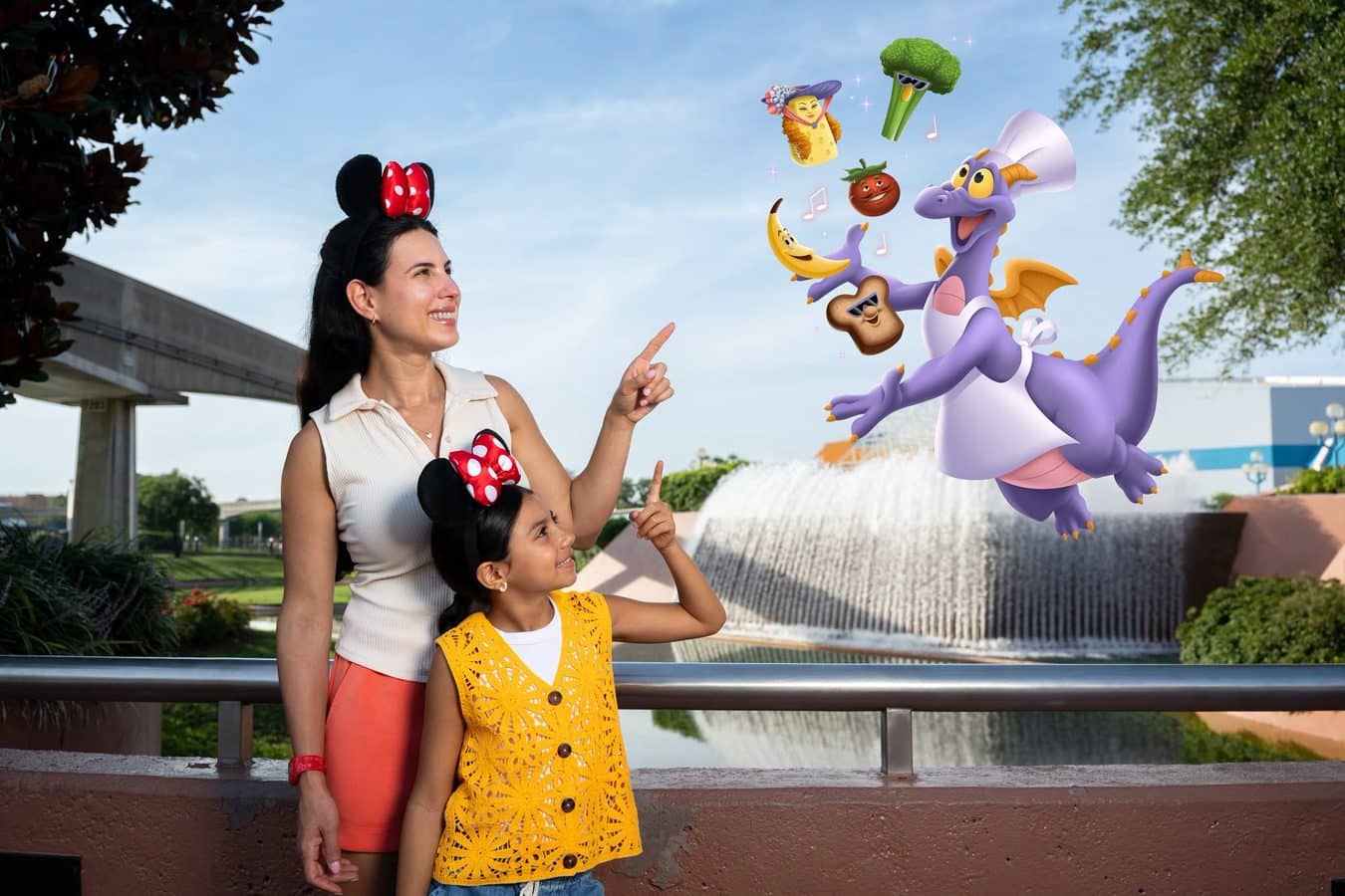 Two smiling girls with Minnie Mouse ears point at a large purple dragon and floating cartoon fruits in an outdoor setting