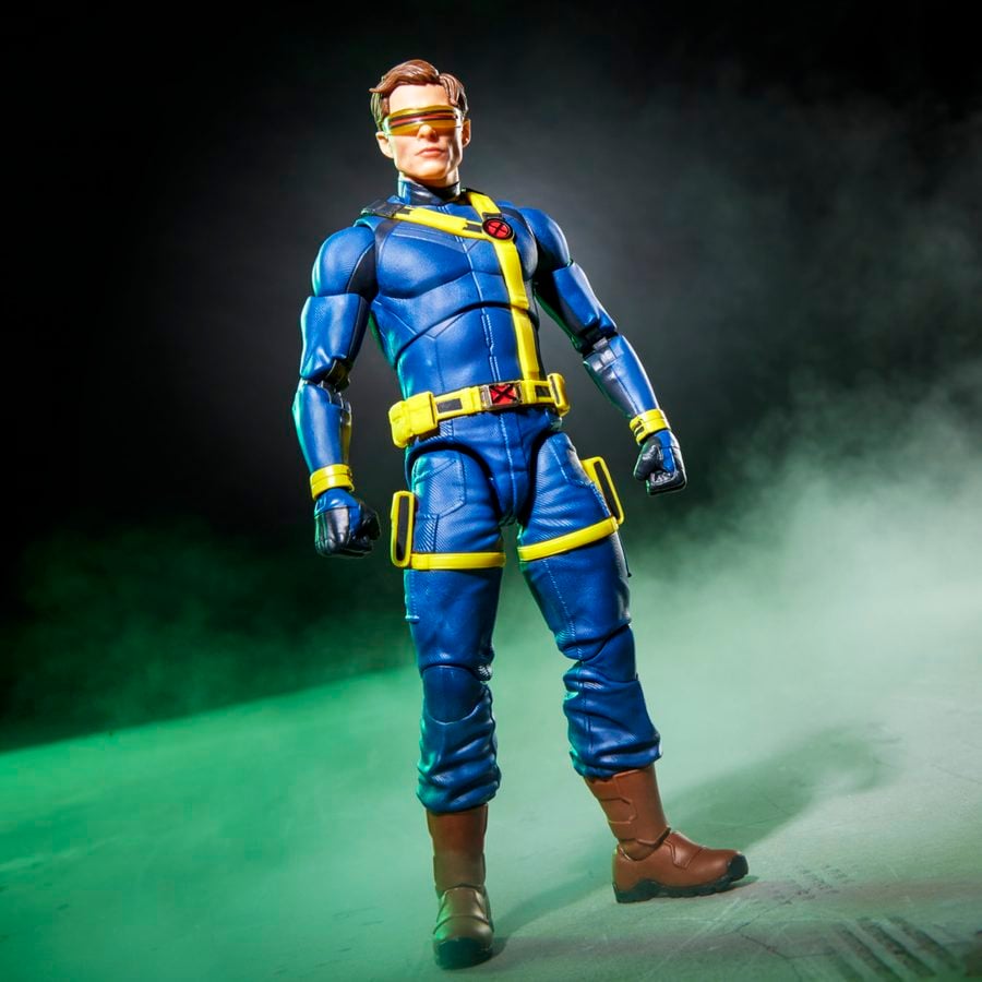 Action figure in a blue suit with yellow harness standing on a green lit smoky stage