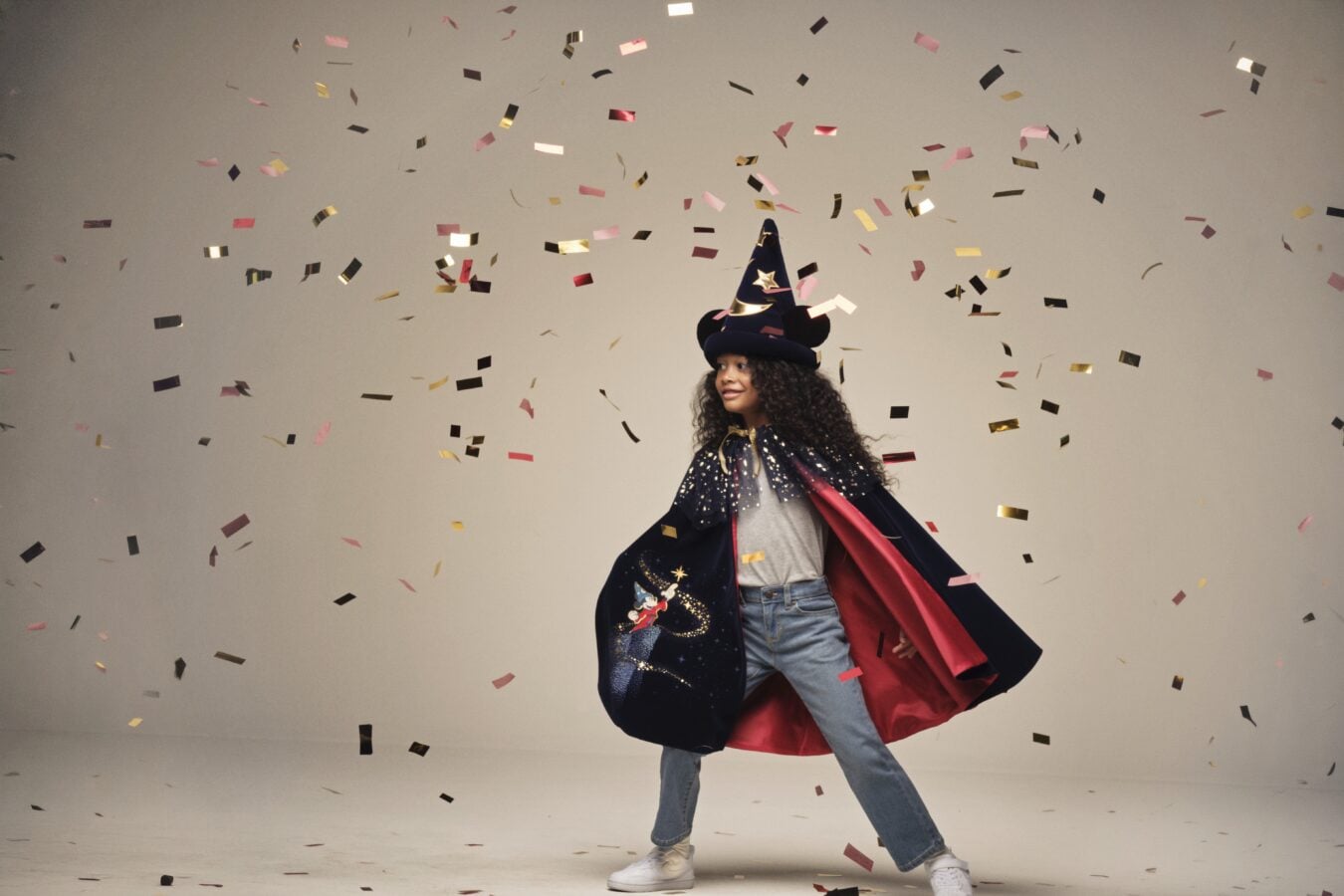 Person in a wizard costume and cape walking through falling confetti at a celebration