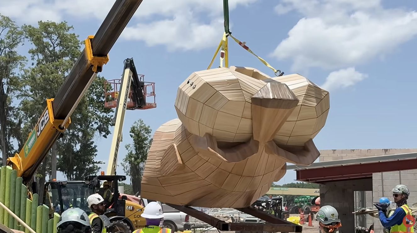 Large wooden duck sculpture being lifted by a crane at a construction site workers in hard hats nearby