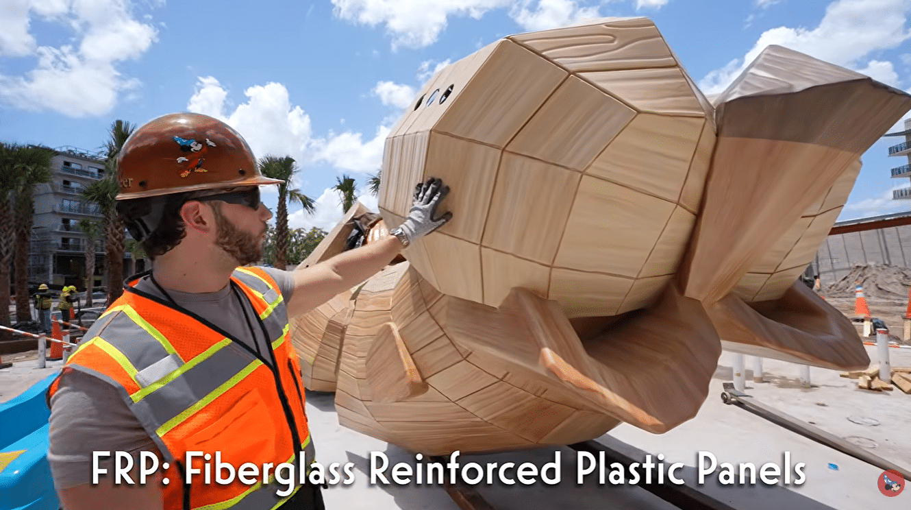 Construction worker in a highvisibility vest and hard hat touches a huge faceted tan sculpture at a sunny construction site with the text FRP Fiberglass Reinforced Plastic Panels across the bottom informative image