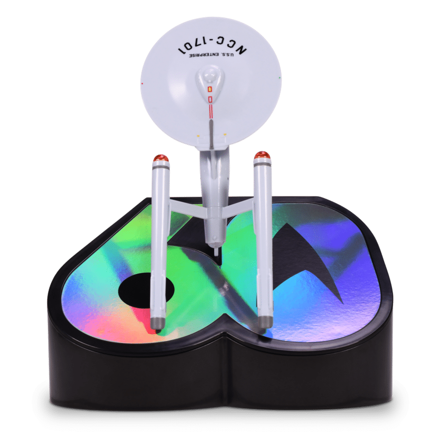 Close up of a colorful circular prize wheel mounted on a gray metal stand showing rainbow segments and a small red indicator