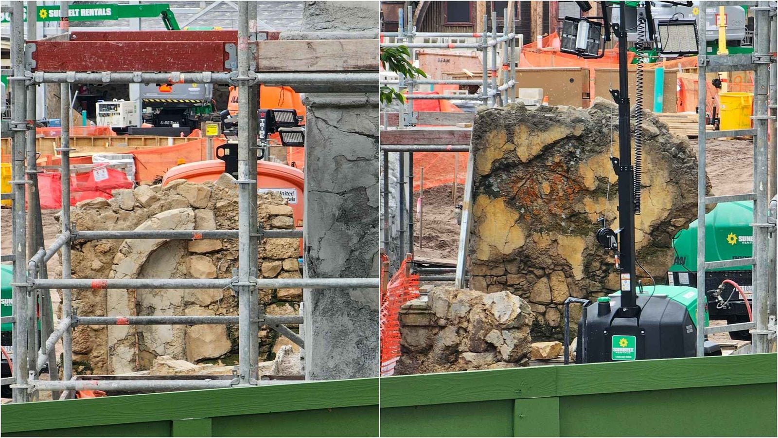 Construction site with metal scaffolding exposed rocks and a compact excavator amid orange safety fencing
