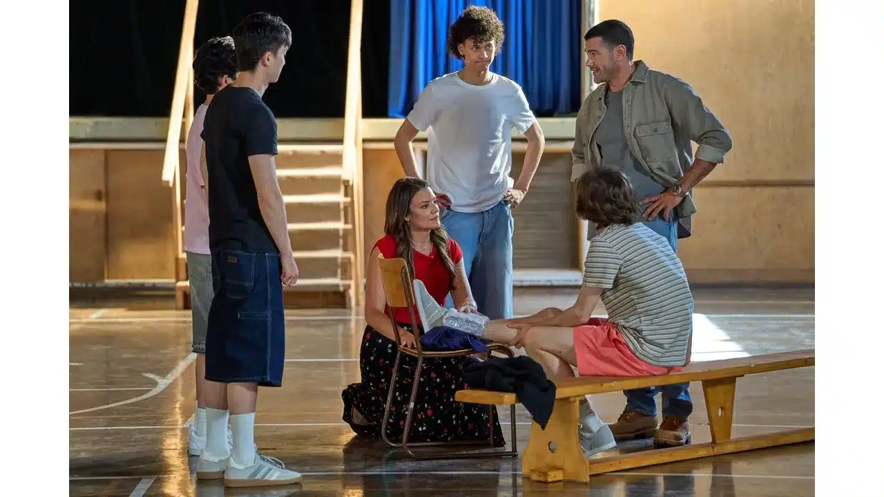 adty2 Fantasy Land News Group of young people in a rehearsal space one person sits on a bench with leg extended while others stand and talk