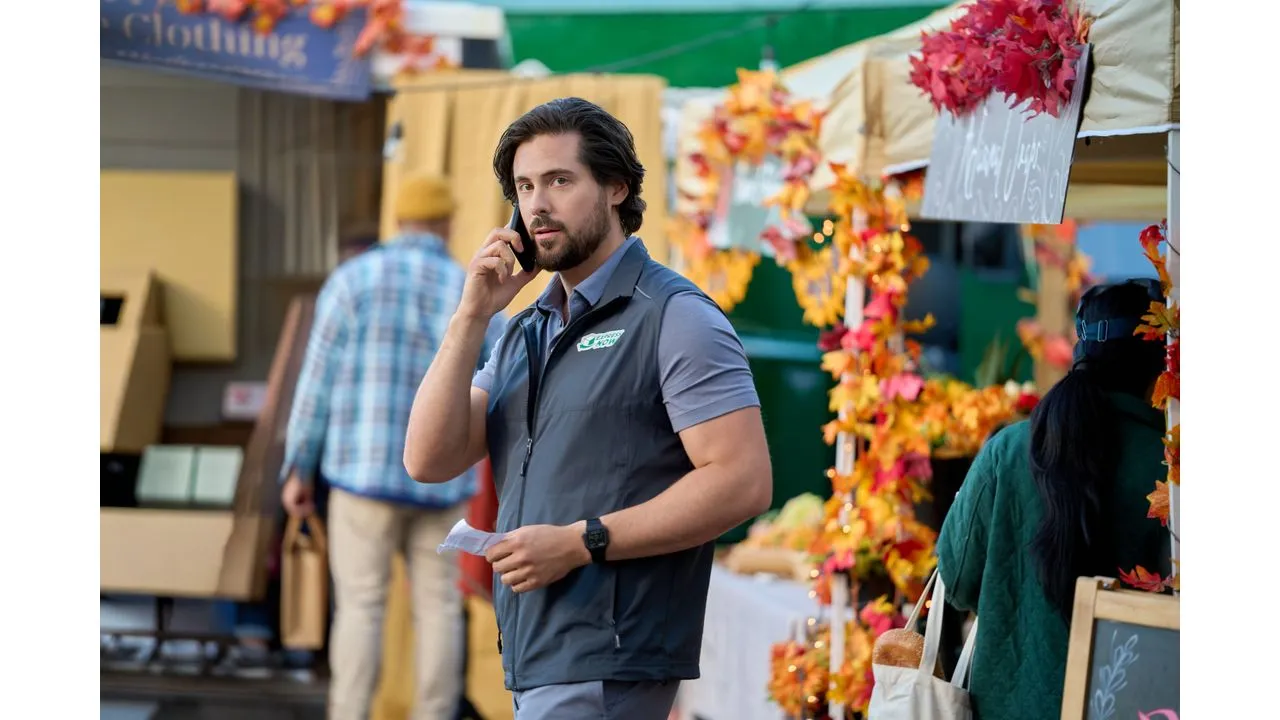 lovec Fantasy Land News Man in a blue gray uniform talks on a mobile phone at an autumn market stall decorated with colorful leaves