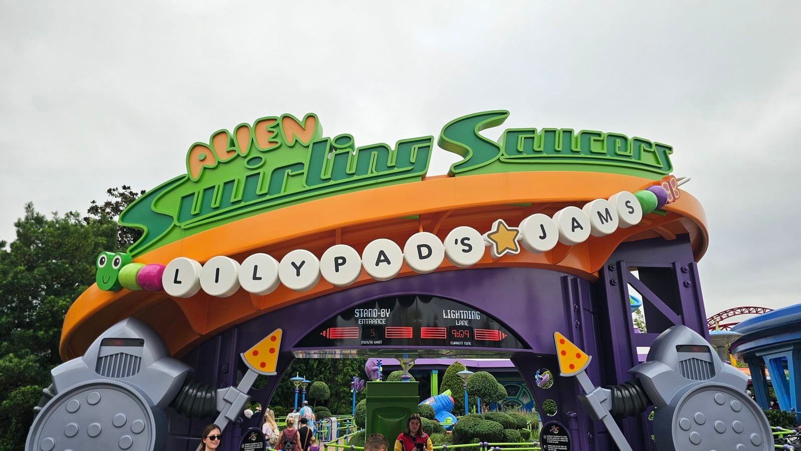 Bright amusement park sign reading Alice in Wonderland in green letters above an orange canopy Informative
