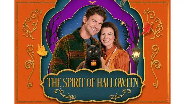 2 Fantasy Land News Smiling couple holding a black cat in front of an orange Halloween poster that reads The Spirit of Halloween