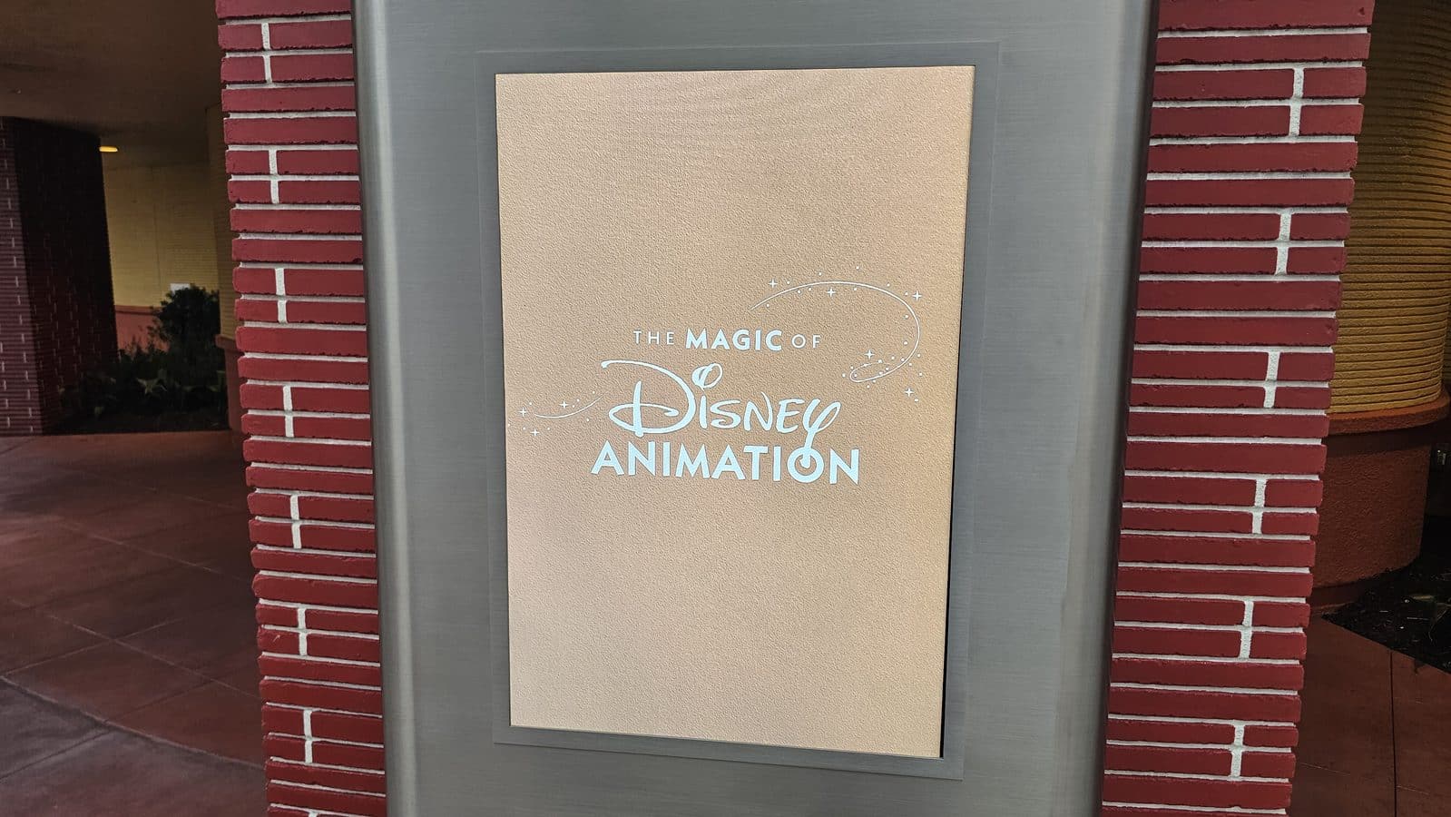 Gold plaque reading The Magic of Disney Animation with decorative stars on a brick backdrop