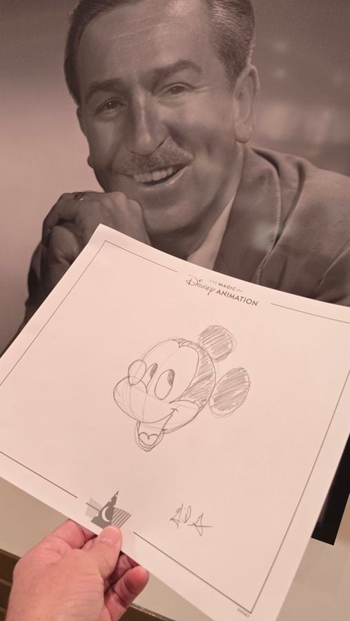 Smiling man with a mustache holding a sheet with a pencil sketch of Mickey Mouse and a Disney Animation header