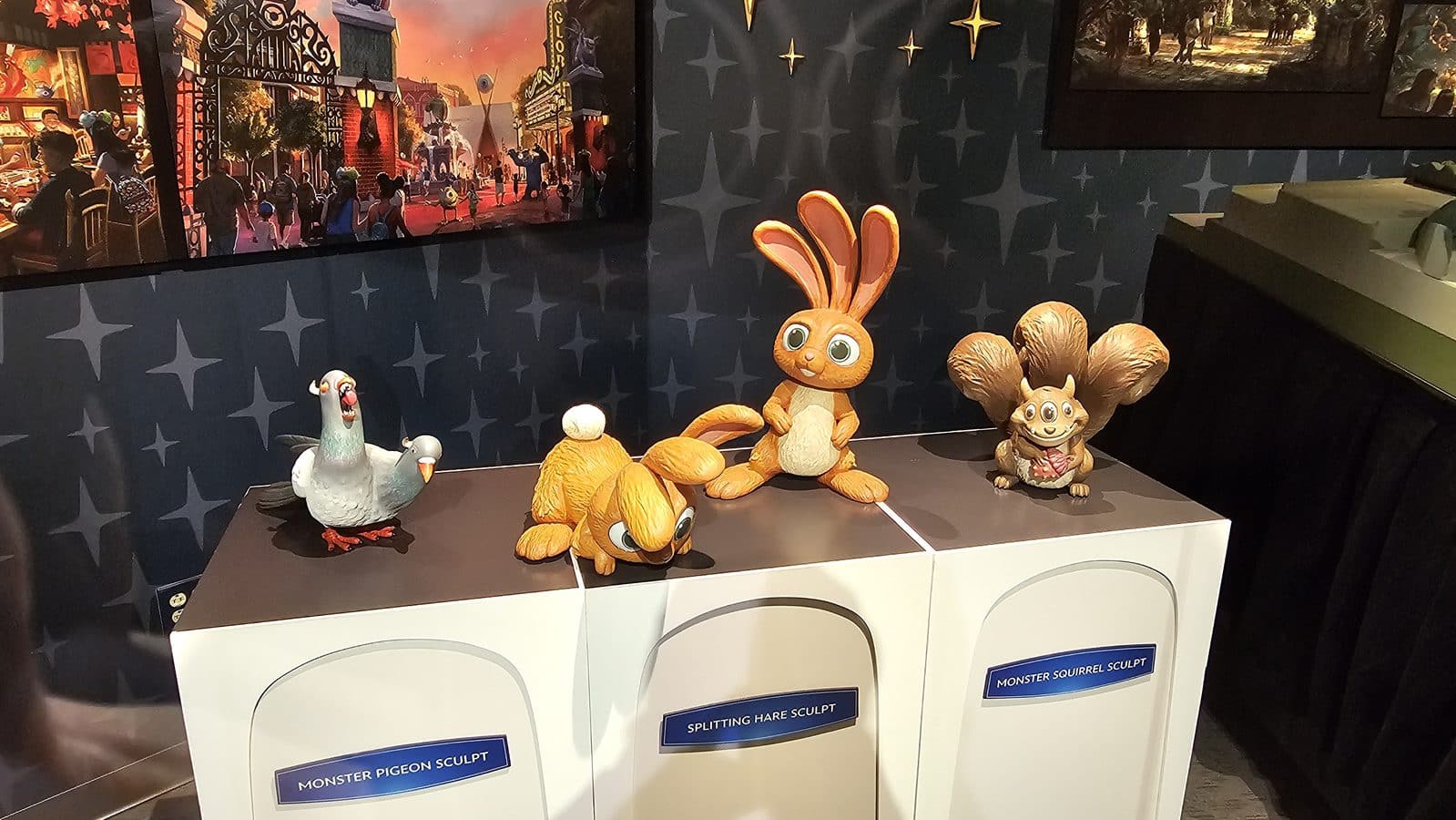 Display of whimsical animal sculptures pigeon hare bunny squirrel atop white display cabinets with label plaques showing sculpture names