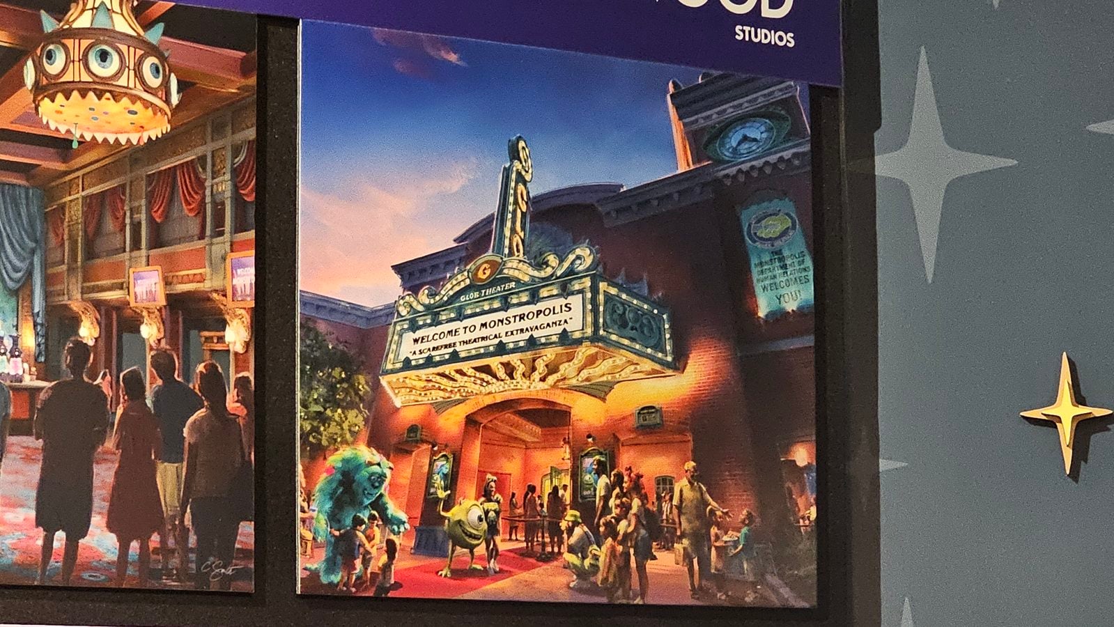 Theater façade with a bright marquee saying Welcome to Monstropolis and a crowd of people outside colorful fantasy creatures nearby