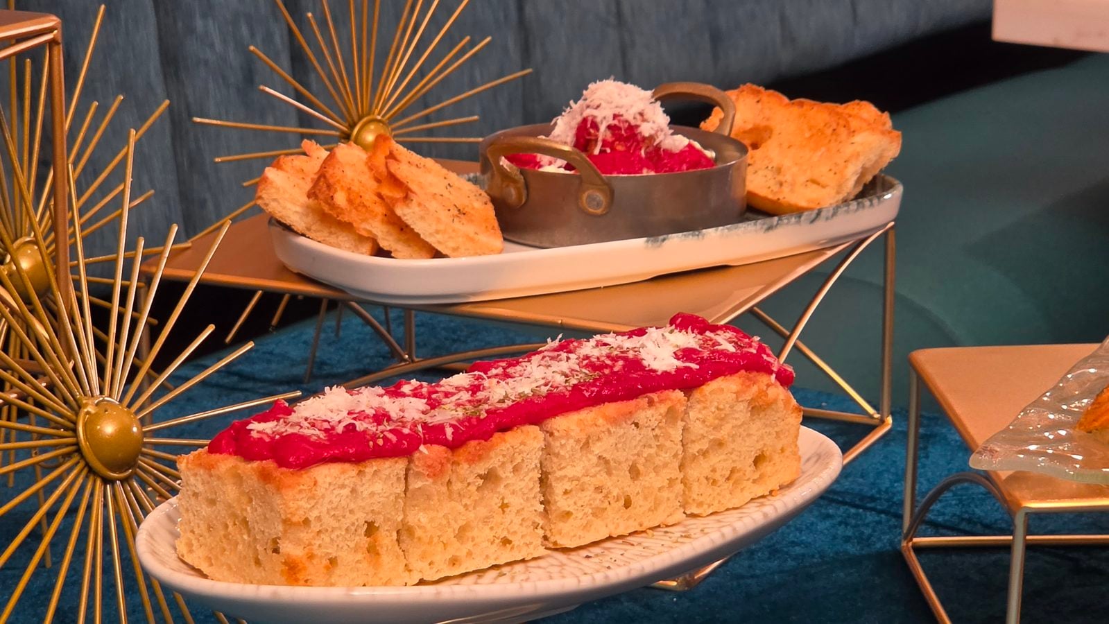Sliced sponge cake with pink icing on a white platter set beside gold starburst decorations