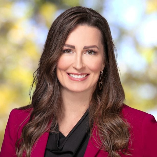 Smiling woman in a magenta blazer and black blouse outdoor blurred background with yellow green bokeh
