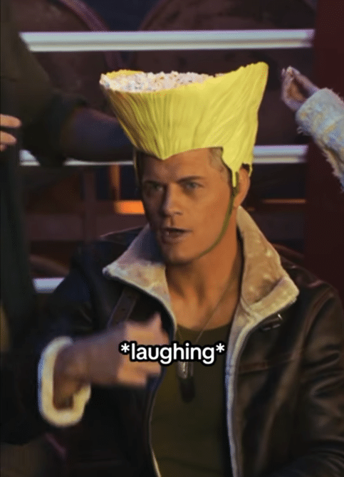Man with bright yellow high volume hairstyle laughs while pointing and talking on a stage