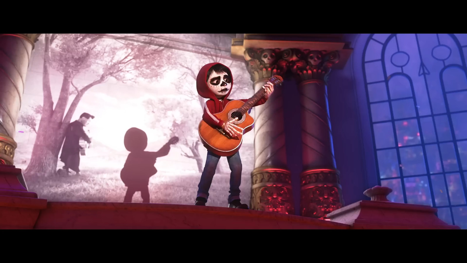 Child in a red hoodie with skull face paint plays an acoustic guitar on a stage with ornate columns and blue purple lighting behind him
