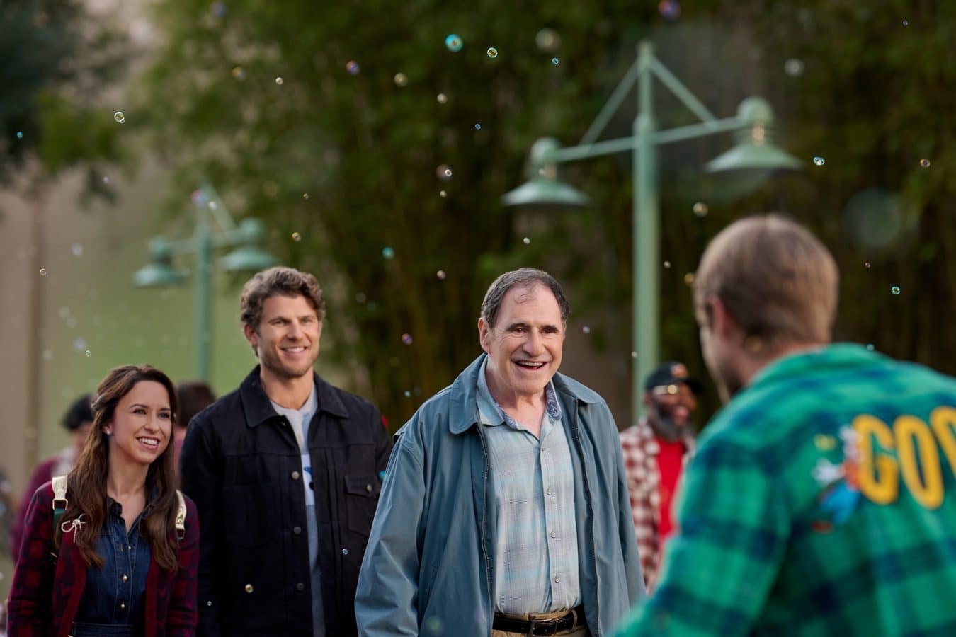 Group of adults smiling outdoors as bubbles float around them during daytime