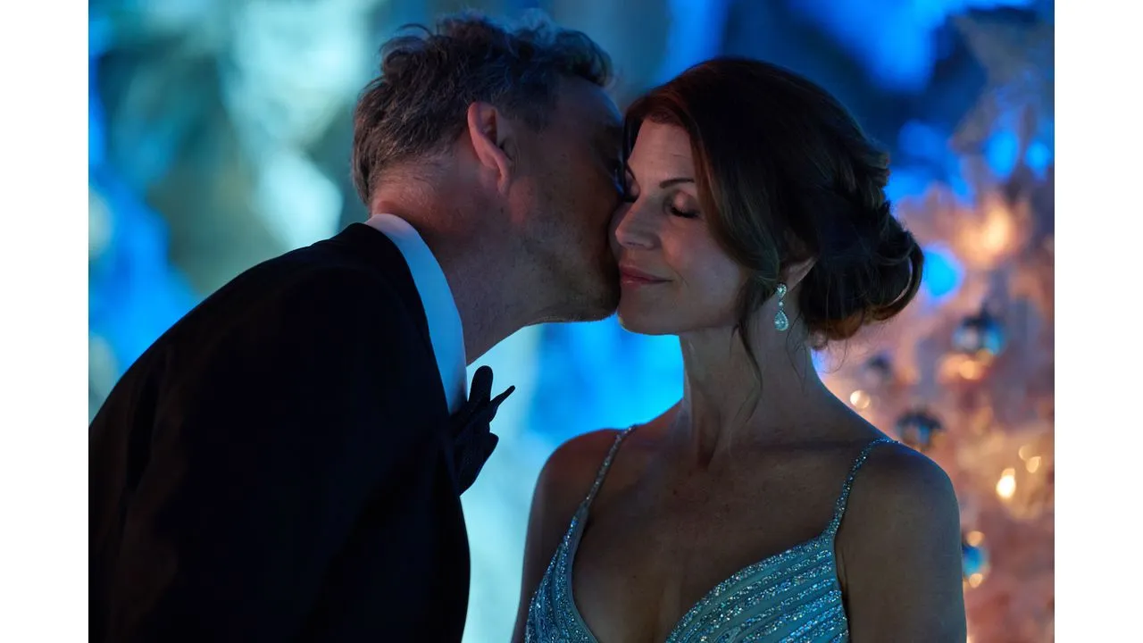 loril Fantasy Land News Man in a tuxedo kissing a woman in a glittering dress at a blue lit evening event