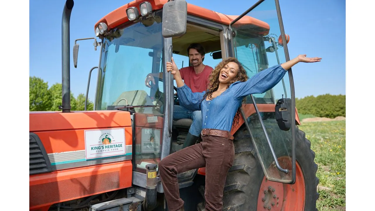 prr1 Fantasy Land News Two people pose cheerfully on a red tractor in a pumpkin farm sunny day and open field in background sign reads Kings Heritage Pumpkin Farm informative promo image
