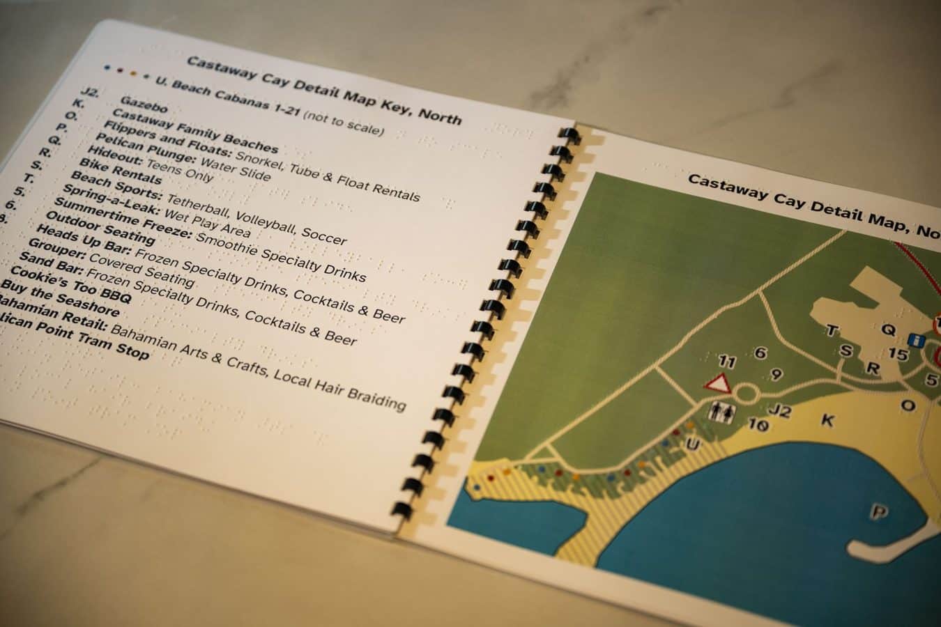 Spiral bound booklet opened to a Castaway Cay detail map key with a colored map on the right
