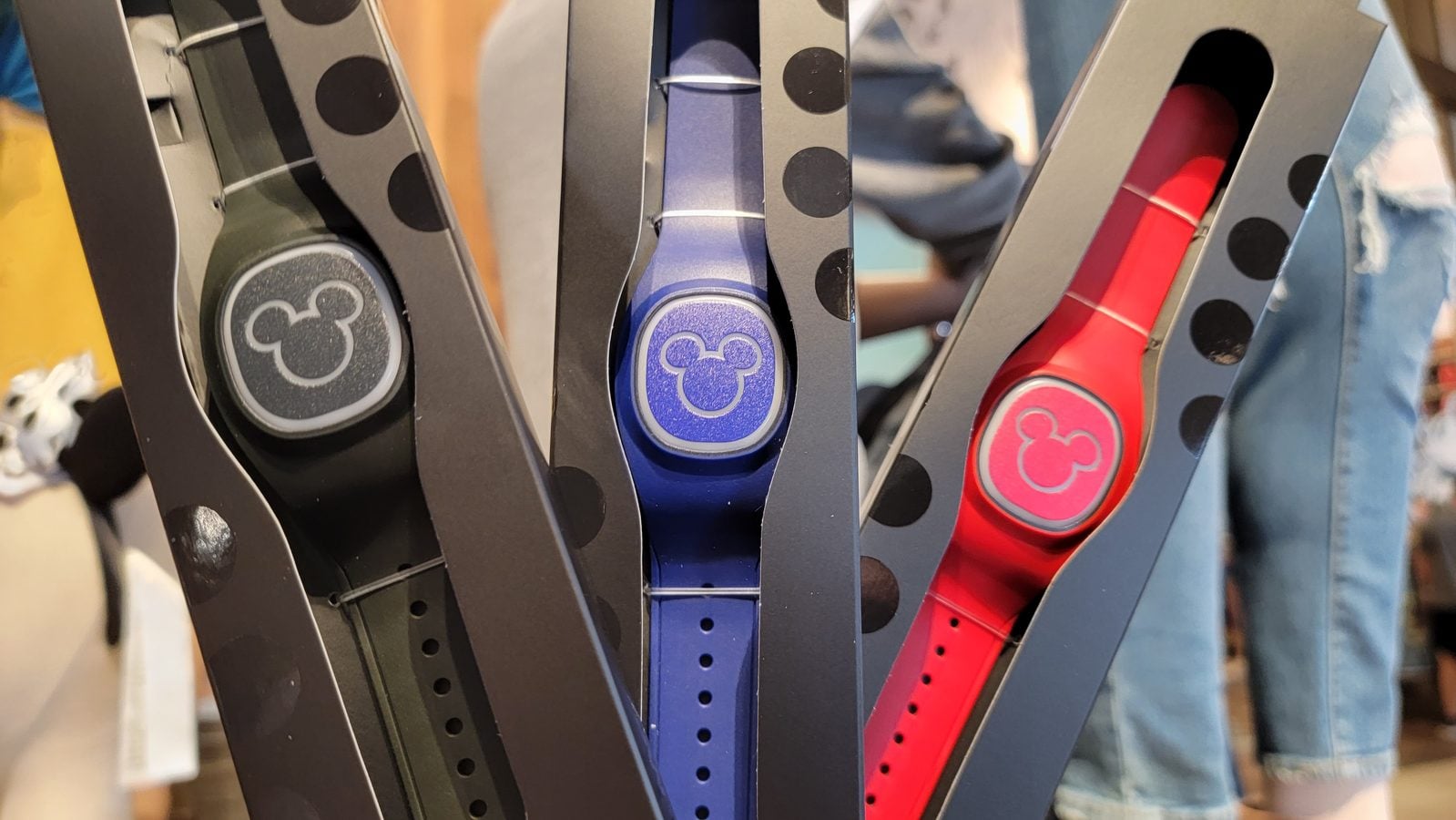 Close up of several belts with Mickey Mouse logo buckles in black purple blue and red on a display rack