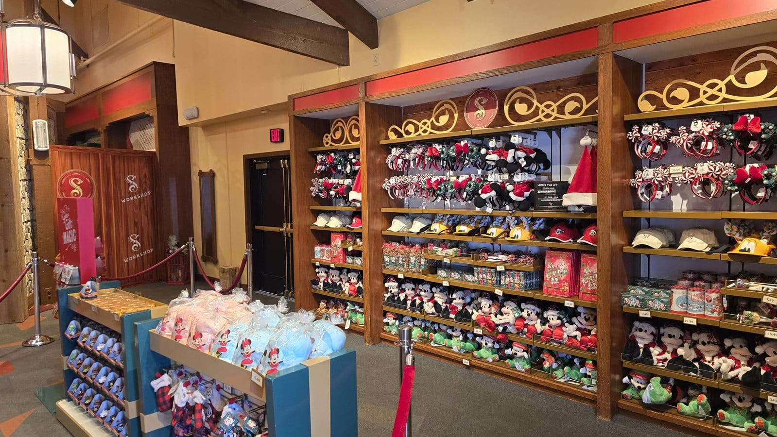 Interior of a souvenir shop with wooden display shelves filled with Christmas themed headbands hats and plush toys on multiple levels