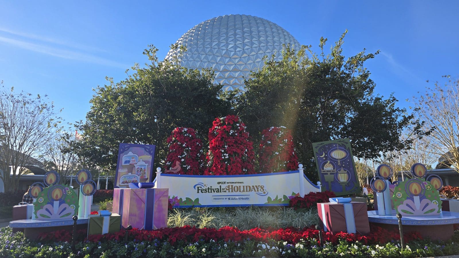 Geodesic sphere behind festive holiday decorations and blooming red flowers in a theme park entrance